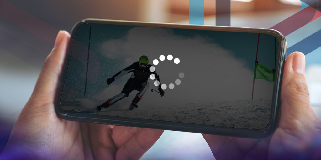 Close in view of someone holding a mobile device horizontally picturing a large buffering signal in the foreground and a downhill skiier in the background,