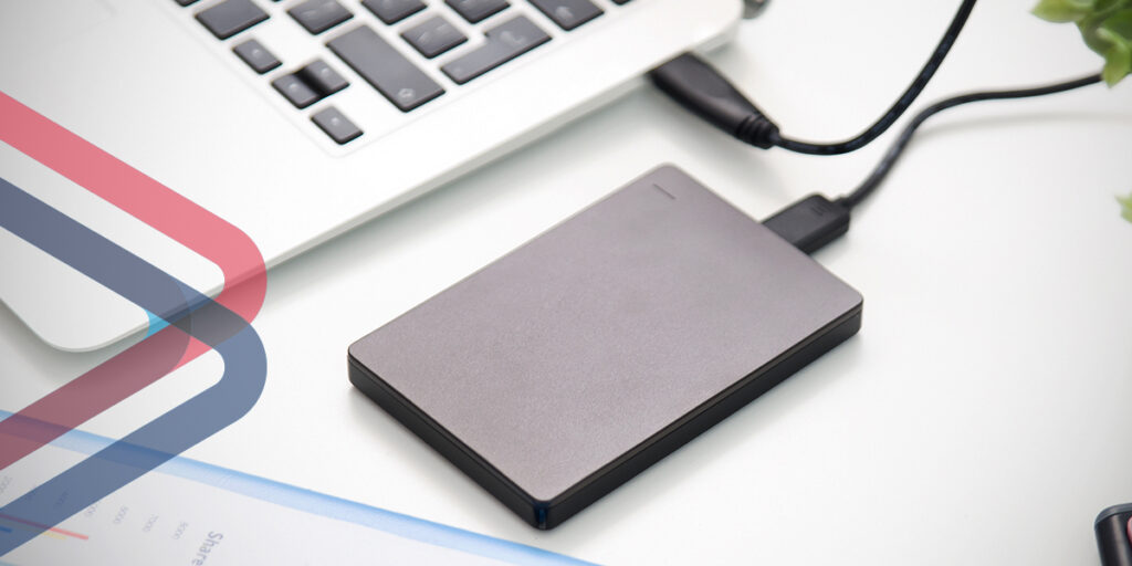 Close-up view of an external hard drive plugged into a laptop.